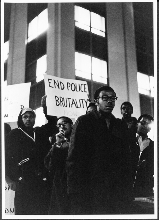 A group of African-American protesters. One person holds a sign that says "End Police Brutality."