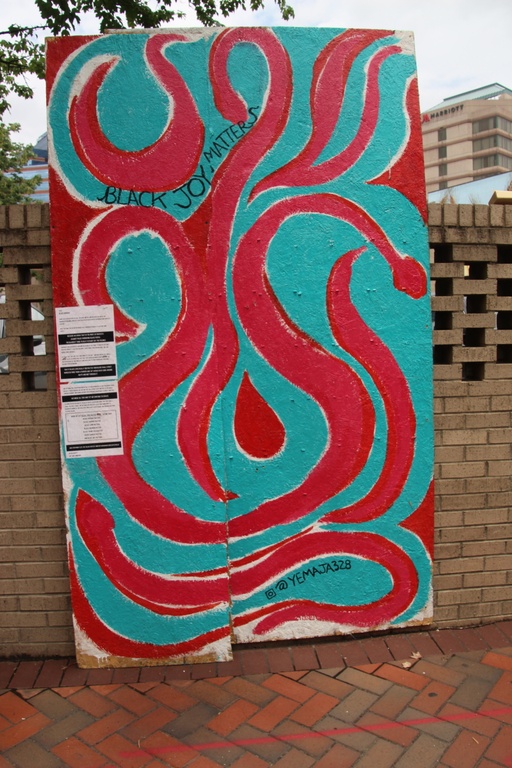 An mural with abstract swirls of red and blue intertwined with the words "black joy matters."