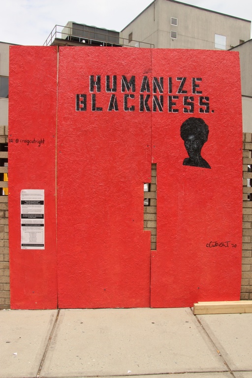 A solid red wall with the face of a black woman and the words "humanize blackness."