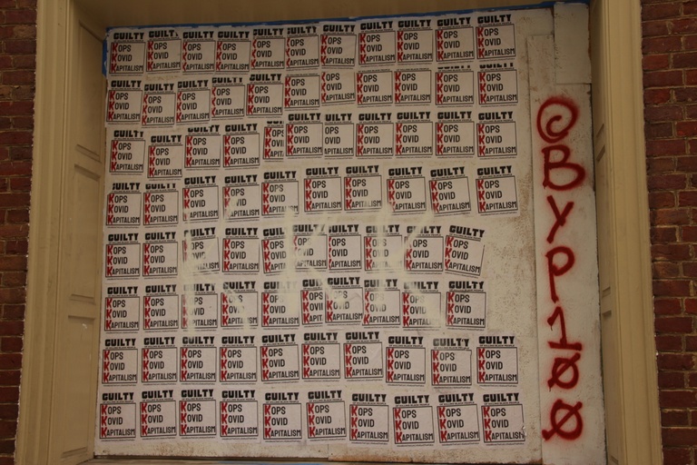 A collage of repeating signs that say "Guilty: Kops Kovid Kapitalism (KKK).